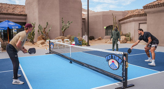 People in the middle of a pickleball game, the net has a logo for Fat Tire beer