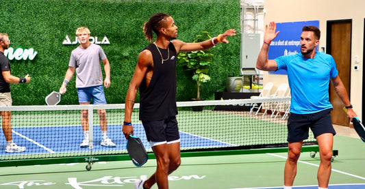 Two pickleball partners celebrate after winning a point.