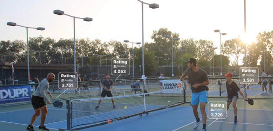 Players play pickleball as the sun sets behind them.